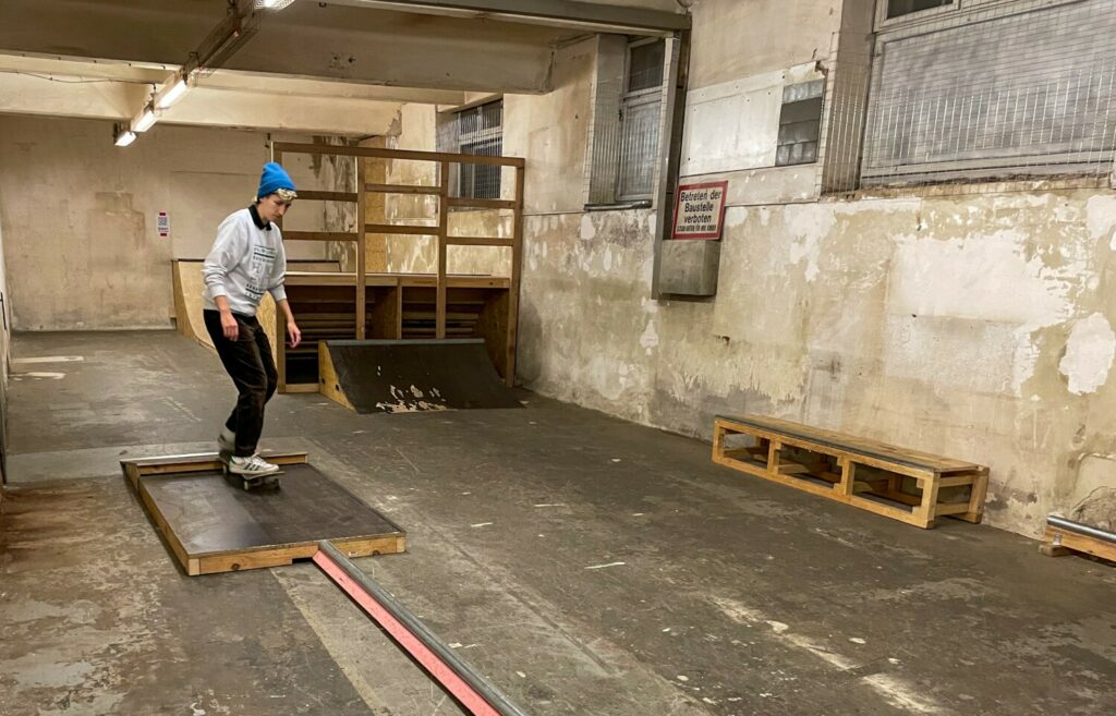 Eine Person fährt mit einem Skateboard über eine Holzrampe.